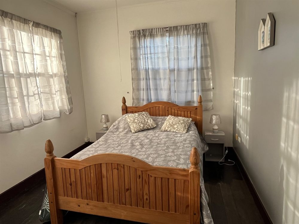 Sunlit double bedroom with a pine bed and bedside lamps
